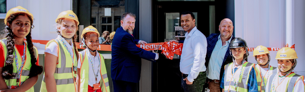 A group of people cutting a ribbon in front of a doorway