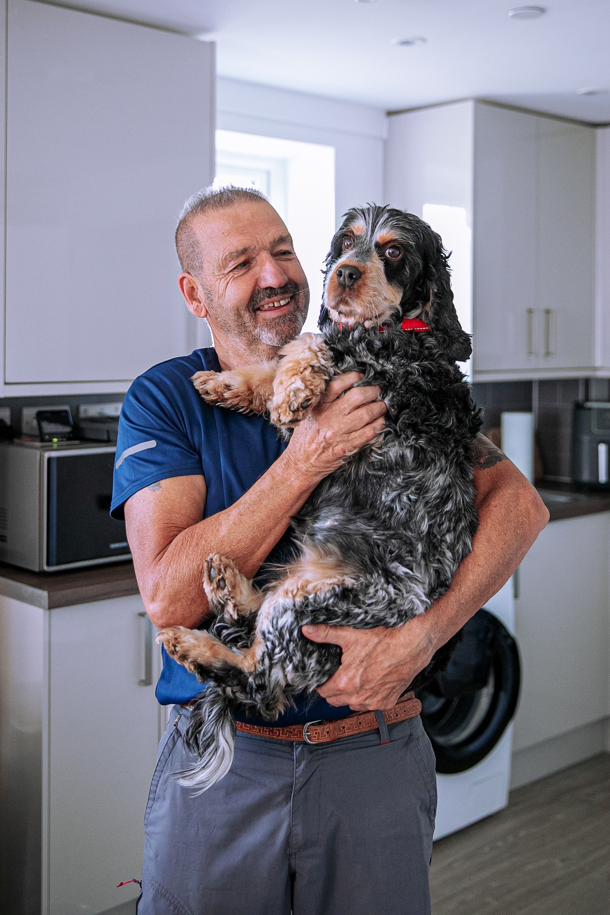 Paul stood in his new kitchen holding his dog Lily. 